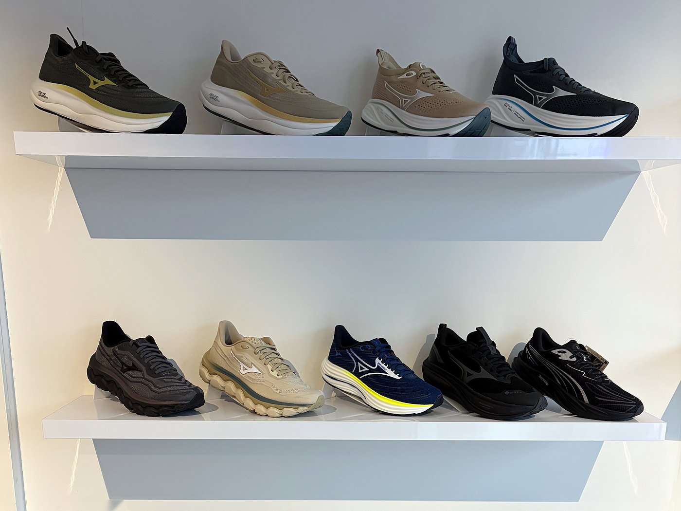 Heren hardloopschoenen van Mizuno en Puma aan de wand bij Sport-Inn Bussum
